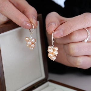 Detail of pink freshwater pearl grape cluster earrings and matching ring on wooden box