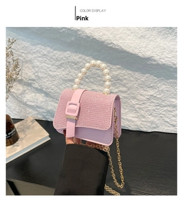Pink rhinestone crossbody bag with pearl handle and golden chain shown in hand