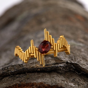 Macro shot of 18K gold S925 silver garnet ring with wavy texture on tree bark