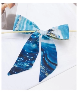 Blue silk scarf headband with abstract star pattern draped over a wooden support