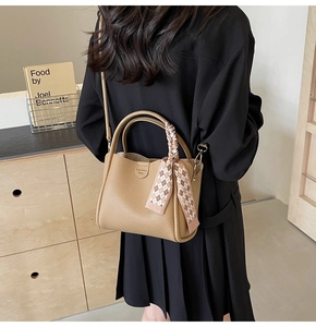Fashionable khaki bucket bag with silk scarf accessory worn by a model in casual setting