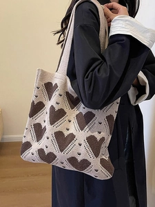 Chic beige knitted tote bag with brown heart patterns shown on a female model shoulder
