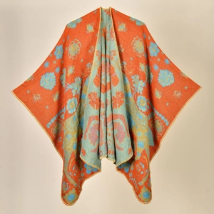 Detail of knitted orange shawl featuring blue floral and peacock patterns with yellow trim