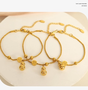 Detail of golden stainless steel bracelet with Fu character and gourd charms