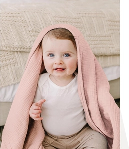 Detail view of pink muslin cotton baby swaddle blanket with soft textured gauze fabric