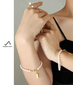 Macro view of 18K gold plated stainless steel bracelet with freshwater pearl and square charm