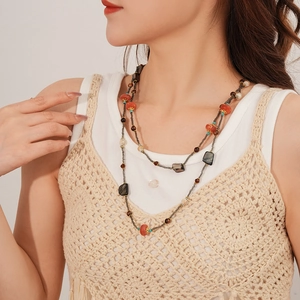 Gros plan d'un collier bohème multicouche avec perles corail rouges et turquoise