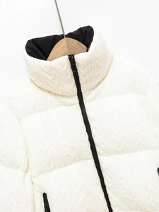 Detailed close-up of white knitted texture ski jacket with black zipper and contrast lining