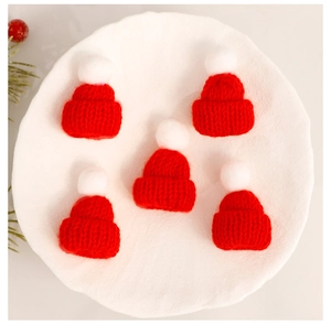 Detailed view of 5 mini knitted Christmas hats with red and white pom poms for DIY crafts