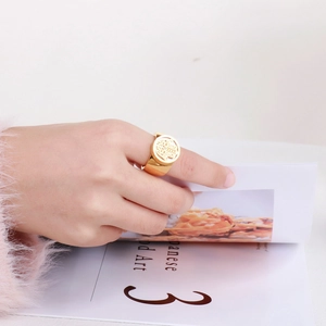 Hamsa Hand gold ring with center diamond shown on hand while flipping a magazine