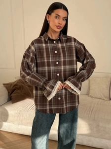 Detailed shot of brown plaid shirt featuring delicate white lace trim on cuffs