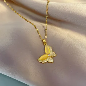Detail of a gold butterfly necklace with yellow gemstone and pavé rhinestones on silk