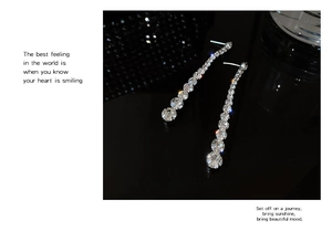 Macro shot of sparkling crystal drop earrings with silver pins on a reflective black base