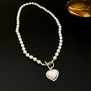 Elegant pearl heart necklace with gold toggle clasp on dark textured background