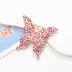 Broche papillon en strass rose avec ailes évidées et cristal arc-en-ciel sur blanc