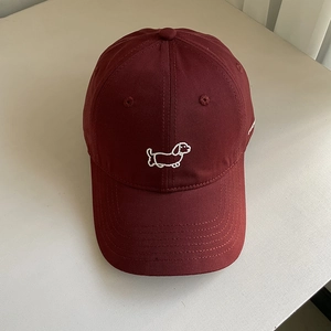 Close-up of cute white puppy embroidery on a deep red cotton canvas baseball cap