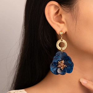 Gros plan d'un mannequin portant des boucles d'oreilles fleur en résine et cristaux ambrés