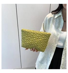 Detail of green floral quilted makeup bag held by a model for a stylish summer look