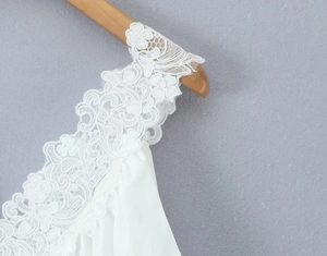Dettaglio ravvicinato del ricamo in pizzo bianco delicato su un abito casual femminile