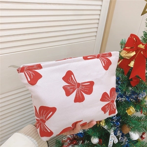 Detail of red bow pattern on canvas makeup bag with silver metal zipper closure