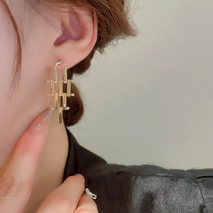 Detailed close-up of golden irregular geometric earrings worn by a woman for a chic look