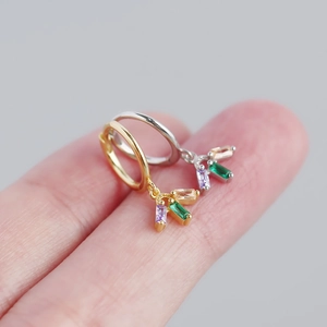 Detail of s925 silver earrings with colorful rectangular zircons held on a finger