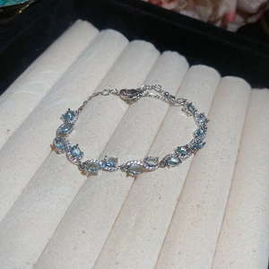 Luxurious silver bow bracelet with light blue oval gemstones on velvet jewelry tray