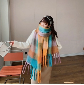Detail of a colorful oversized checkered scarf featuring bright orange and blue with long tassels