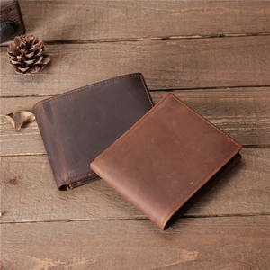 Retro men's leather wallets in brown tones on a rustic wooden background with pine cones