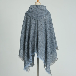 Detail of blue knit poncho cape showing hooded design and irregular fringe edges