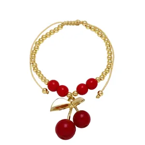 Detail of adjustable beaded cherry bracelet with gold beads and red fruit pendant