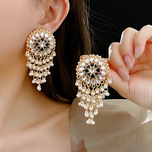 Close-up of vintage gold tassel earrings with black enamel flower and faux pearls