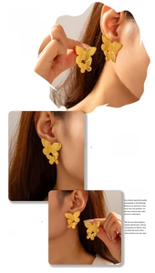 Model display of golden butterfly earrings with textured geometric design in titanium steel