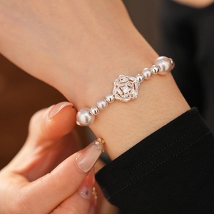Detail of silver flower pearl bracelet with sparkling zircons on a woman's wrist