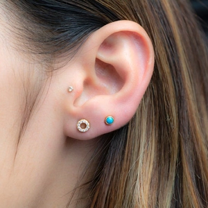 Detailed view of turquoise stud and gold pave hoop earring set on female ear