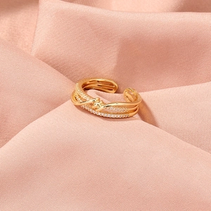 Detail of gold safety pin ring with micro-pave cubic zirconia on pink silk background