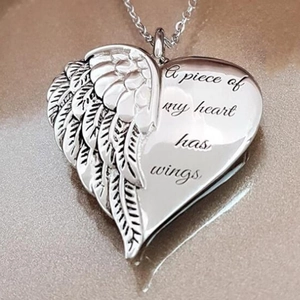 Macro shot of silver heart pendant with wing relief and engraved poetic message
