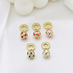 Golden sphere pendants with colorful enamel spots on elegant white silk background