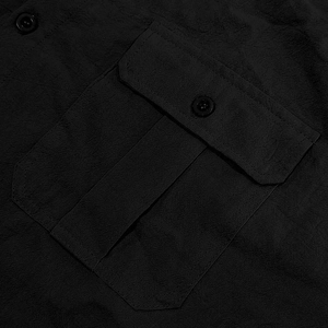 Close-up of black linen shirt showing textured fabric detail and chest pocket stitching