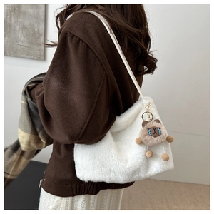 Detail of soft white plush shoulder bag with brown bear keychain for winter fashion