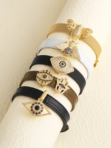Detail of leather wrap bracelets featuring gold bee, evil eye and hamsa hand charms
