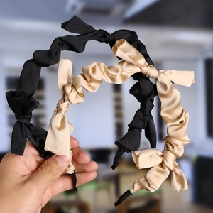 Detail of twisted satin headbands in black and beige with smooth glossy texture