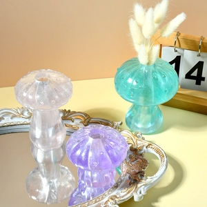 Three textured resin mushroom vases in pink, purple, and cyan on a gold mirror tray