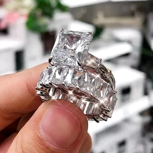 Detailed close-up of emerald-cut engagement ring set with matching eternity band