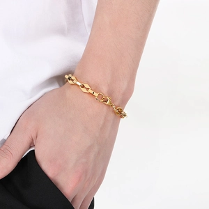 Vue détaillée d'un bracelet à maillons géométriques dorés porté au poignet sur un haut