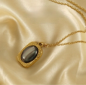 Close-up of a vintage 18K gold-plated stainless steel necklace with dark natural stone pendant