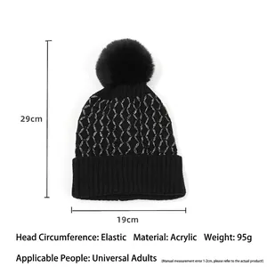 Women's black knit beanie with silver thread plaid pattern and fluffy pompom detail
