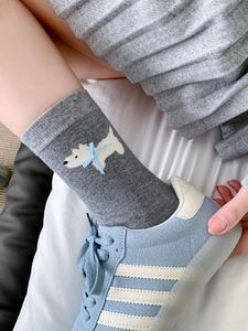 Primo piano di calze di cotone grigie con jacquard a cucciolo bianco e dettaglio fiocco blu