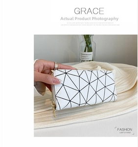 Detail of white geometric triangle long wallet held by hand with gold metal zipper