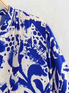 Detail of blue and white abstract print dress featuring pleated shoulder design